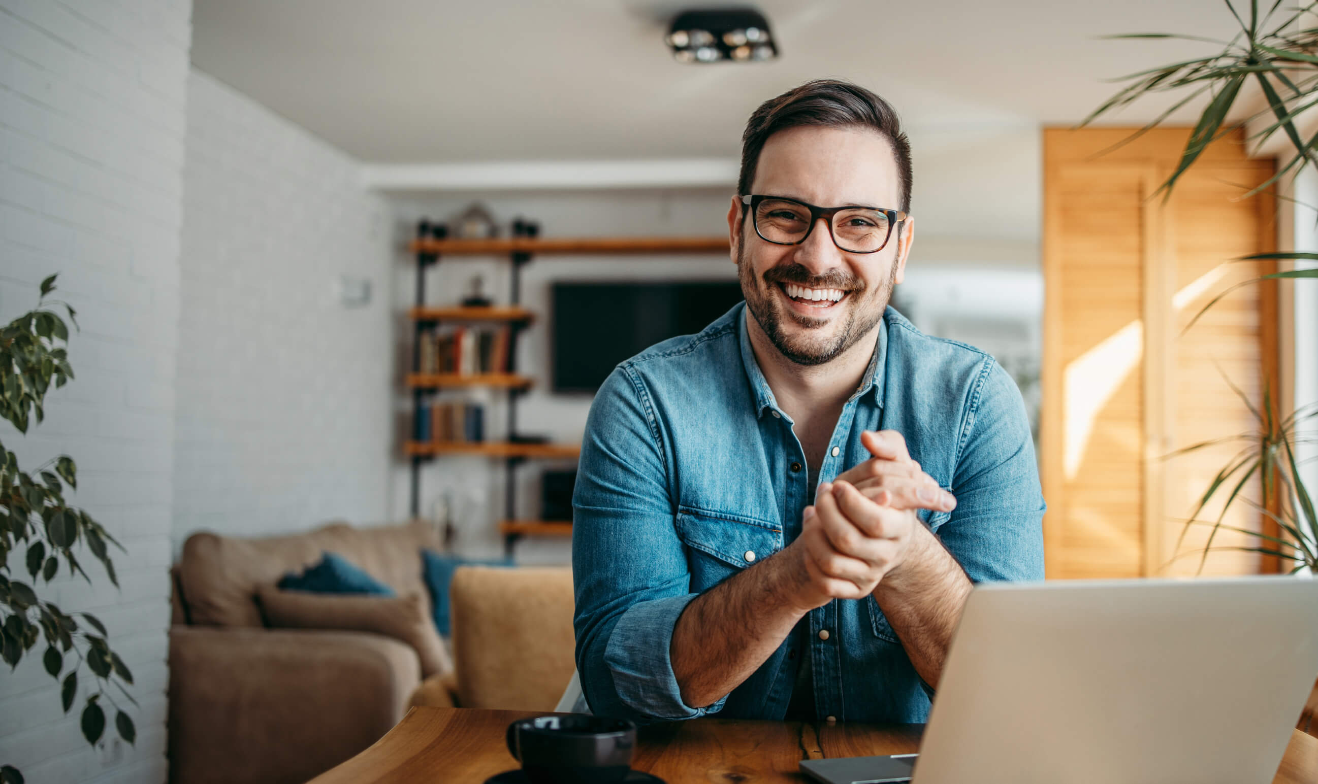 Photo of a man in glasses smiling in front of his laptop